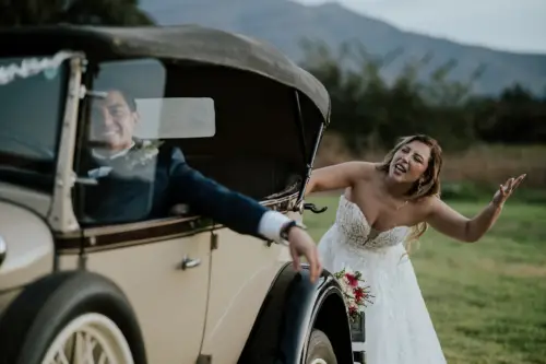 Novia empujando el auto moleta y novio feliz en el auto