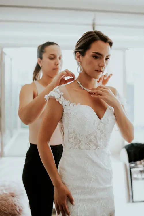 Novia en sus preparativos antes del matrimonio ajustando su collar