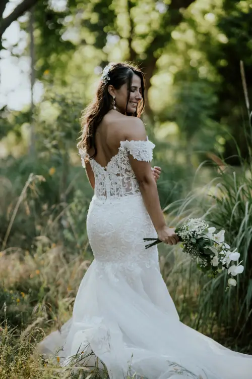 Novia feliz con el vestido y ramo de novia de espalda